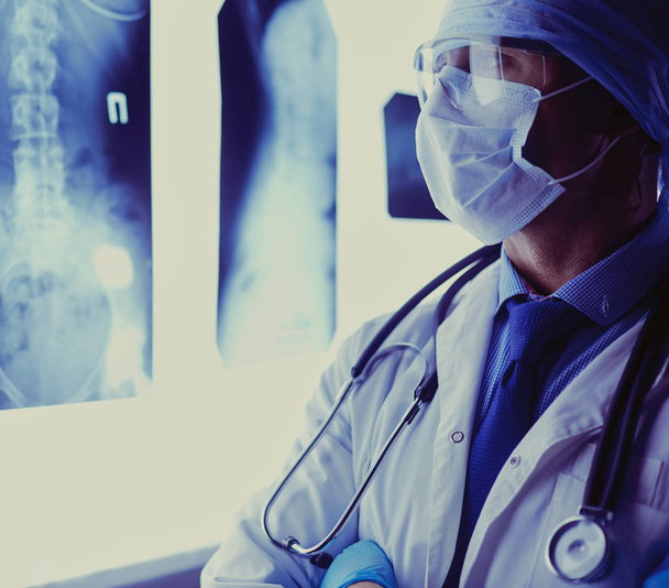Junger Arzt sucht Röntgenbild auf isoliertem weißen Hintergrund - Foto, Bild