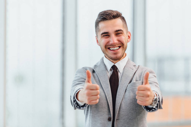 Successful businessman with thumbs up celebrating his victory, smiling at the camera. - Foto, imagen