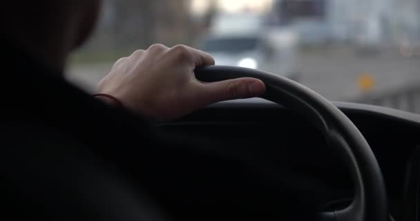 Een close-up van een mans handen die een stuurwiel vasthouden vanuit het interieur van een auto die over een snelweg rijdt. - Video