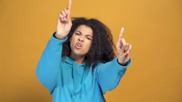 Portrait of a little bit brutal looking afro american woman dancing and singing, Yellow background. Slowmotion. - Záběry, video