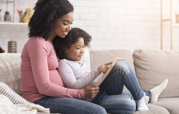 Enceinte afro maman et fille passer du temps à la maison, livre de lecture
 - Photo, image