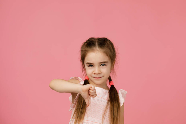 Cute little child girl showing the thumbs down gesture - Foto, imagen