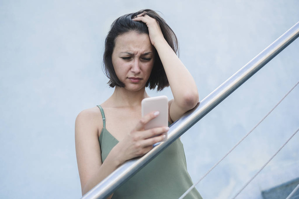 Sad Woman online-inhoud van smartphones in de stad controleren - Foto, afbeelding