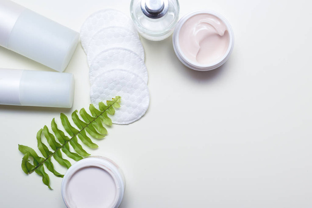 Productos de limpieza facial y recipientes con cremas faciales y almohadillas de algodón
 - Foto, imagen