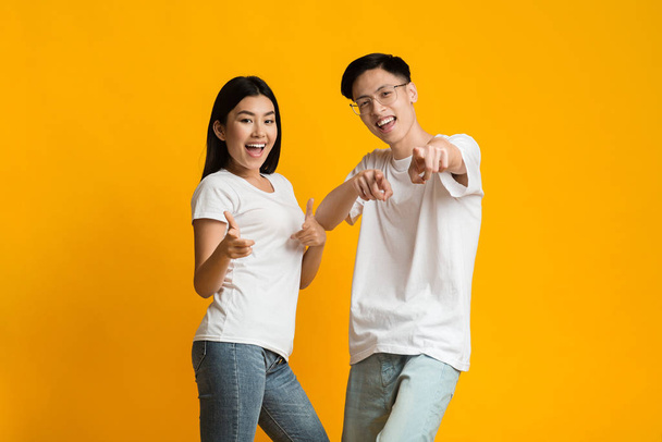 Happy asian couple having fun over yellow background - Φωτογραφία, εικόνα
