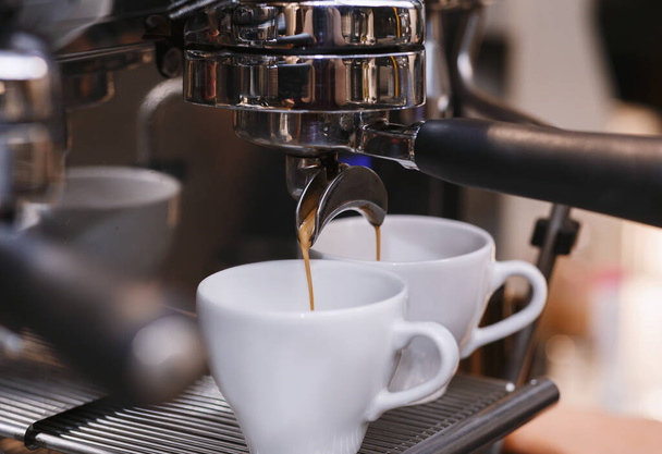 Nahaufnahme einer funktionierenden Kaffeemaschine, Barista, der Espresso im Coffeeshop zubereitet - Foto, Bild