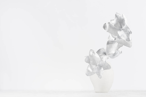 Elegant white home decor - white ceramic vase decorated silver leaves on light white wood table. - Foto, afbeelding