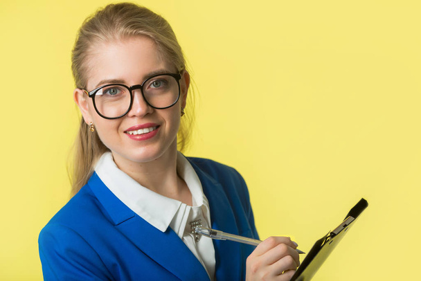 beautiful young woman in a blue jacket on a yellow background - Foto, imagen