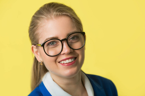 beautiful young woman in a blue jacket on a yellow background - Foto, afbeelding