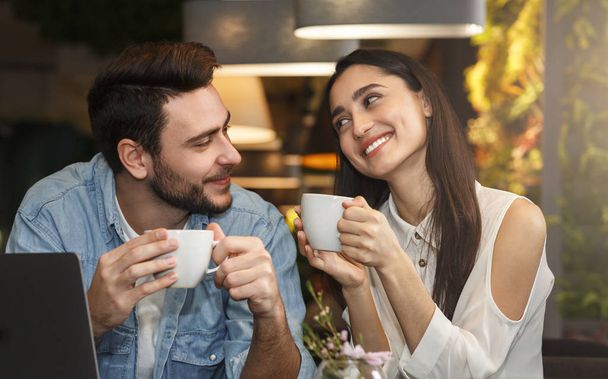 Piękne millennial para korzystających kawy siedzi w kawiarni - Zdjęcie, obraz