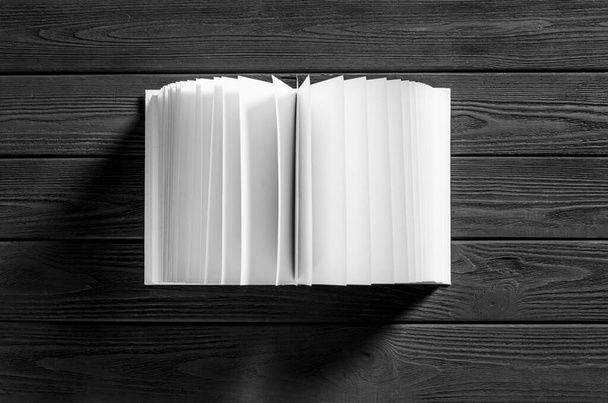 Ein weißes Buch mit weißen Seiten liegt auf schwarzem Holzgrund. Nahaufnahme - Foto, Bild
