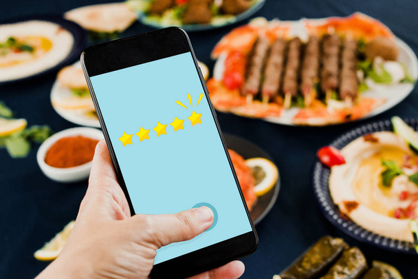 Valutazione stelle su uno smartphone con cibo sullo sfondo. Concetto app ristorante
 - Foto, immagini