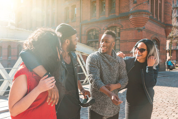 Multiracial group of friends having fun and laughing together - Four people, with different ethnicities and wearing urban style clothes, sharing time together in Hamburg - Lifestyle and friendship - 写真・画像