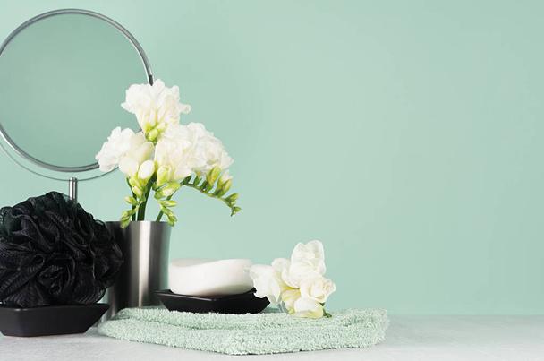 Fashion toiletry accessories in black and silver color in green mint menthe and white interior - mirror, towel, soap, bath puff, spring fresh flowers, closeup. - Fotó, kép