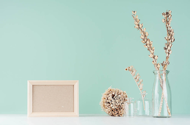 Home decorations in eco style - beige wooden blank frame, dried plant bunch and flowers in glass vase in green mint menthe interior on white wood board. - Foto, Imagem