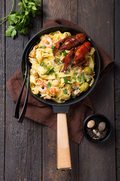 Seafood fettuccine pasta with crayfishes, octopus shrims, on stone pan. Gourmet dish - Fotó, kép