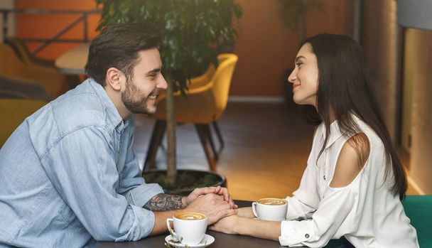 Poikaystävä ja tyttöystävä tilalla kädet flirttailu kahvilassa, Side View
 - Valokuva, kuva