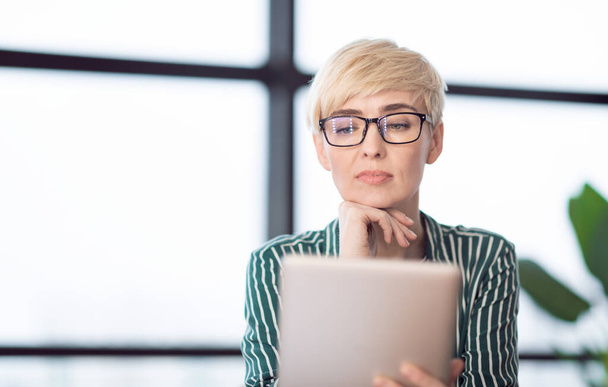 Dame mit digitalem Tablet liest Geschäftsnachrichten im Büro - Foto, Bild