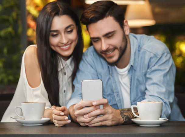 Petit ami et petite amie en utilisant Smartphone assis à la cafétéria
 - Photo, image