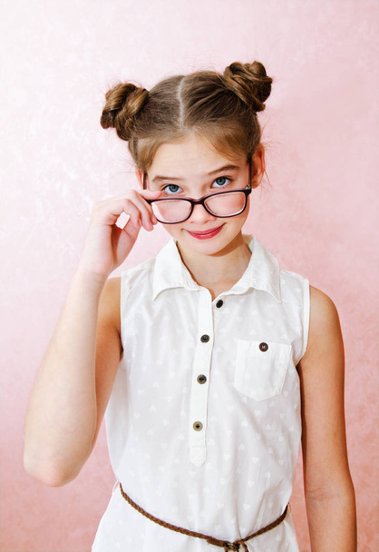 Portrait of funny smiling little girl child wearing glasses isolated on a pink background - Fotografie, Obrázek