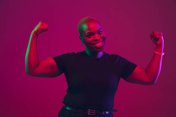 African-american young womans portrait on purple pink background - 写真・画像