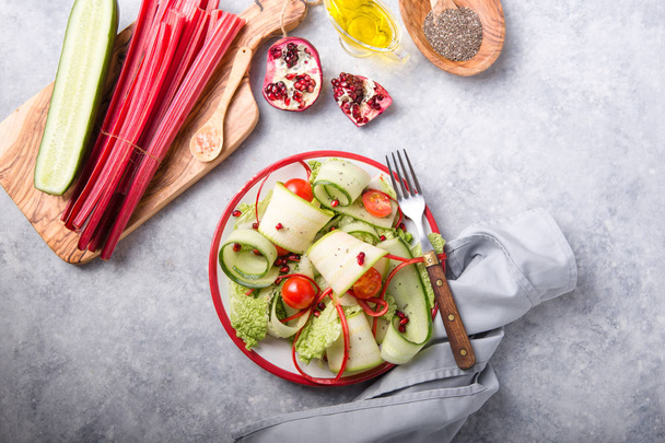 Egészséges vegán diéta saláta friss zöldségekkel - cukkini, uborka pekingi káposzta, paradicsom, mángold és gránátalma magvakkal.Vegán ételek koncepciója. - Fotó, kép