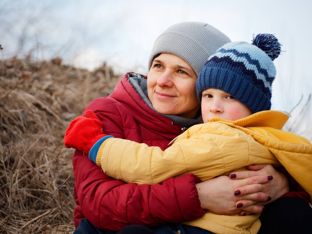μητέρα με ένα μικρό γιο αγκαλίτσες στη φύση το φθινόπωρο του 2020 - Φωτογραφία, εικόνα