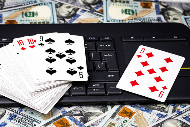 百ドル札、トランプのデッキと黒いキーボード。オンラインカードゲーム、カジノまたはポーカーの概念。オンラインギャンブル. - 写真・画像