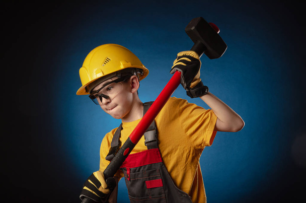 het kind de bouwer kostuum poseren met een werk tool - Foto, afbeelding