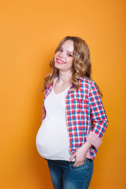 Happy pregnant woman with big belly on yellow background - Фото, изображение