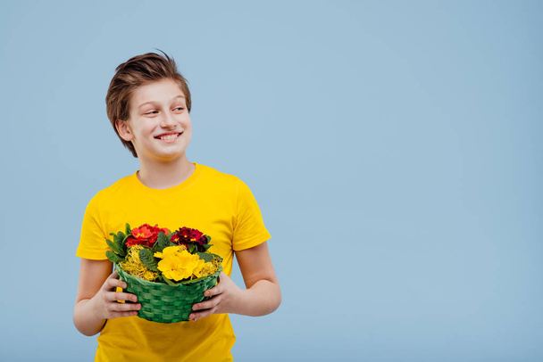 happy preteen boy with basket of flowers in his hand, - Фото, зображення