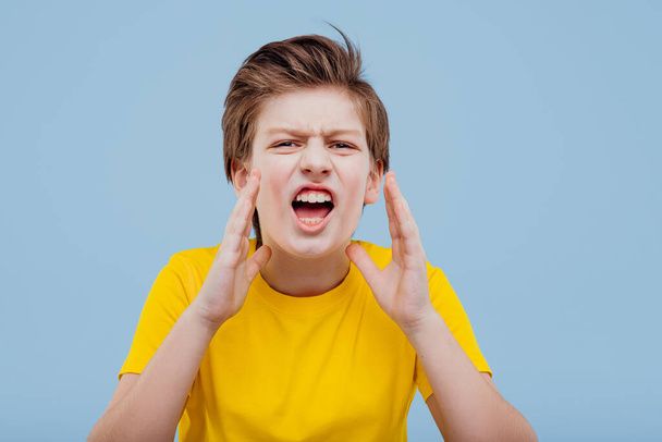 screaming preteen boy looks at the camera - Foto, afbeelding