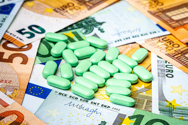 Pastillas verdes en el fondo de los billetes de euro. Concepto del coste costoso de la asistencia sanitaria o de la financiación de la medicina
. - Foto, Imagen