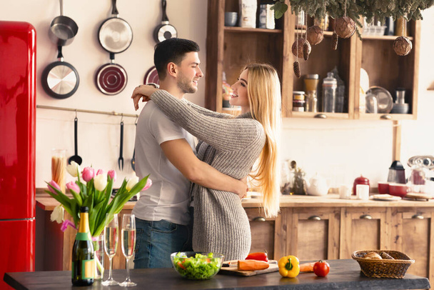 Genç çift mutfakta kahvaltı yaparken birbirlerine sarılıyorlar. - Fotoğraf, Görsel