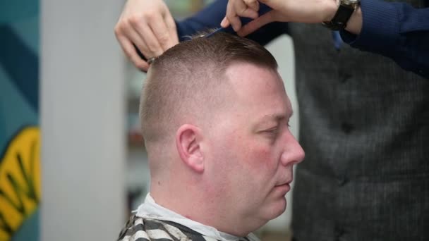 Corte de pelo para hombre en la barbería. Primer plano del maestro cortando un pelo de mans con con clipper - Imágenes, Vídeo