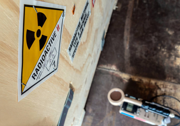 Strahlenmessgerät, das radioaktives Material in der Verpackung erkennt. Ionisierendes Strahlungsrisiko-Symbol auf der Verpackung - Foto, Bild
