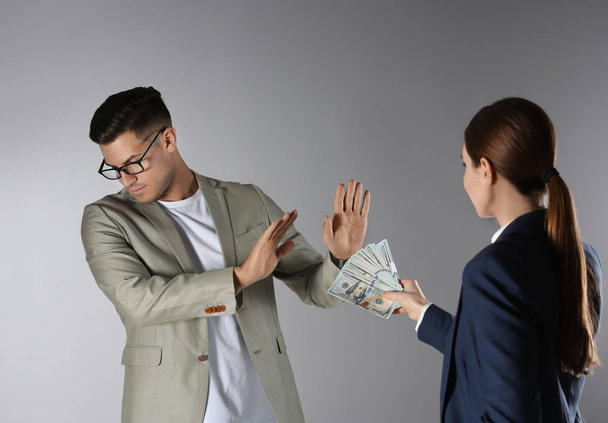 Man refusing to take bribe on grey background - Фото, изображение