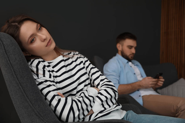 Man preferring smartphone over his girlfriend at home, focus on woman. Relationship problems - Фото, зображення