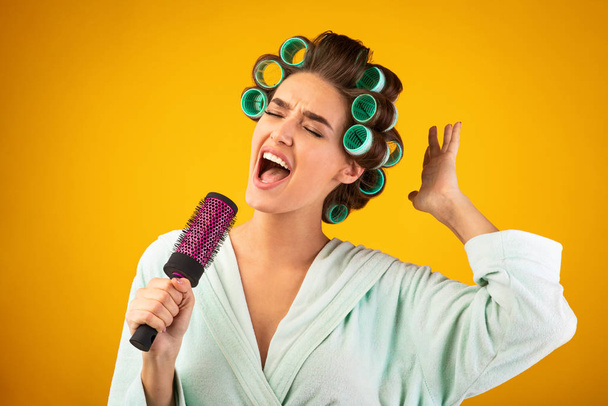 Ama de casa cantando sosteniendo cepillo de pelo como micrófono, Studio Shot
 - Foto, Imagen
