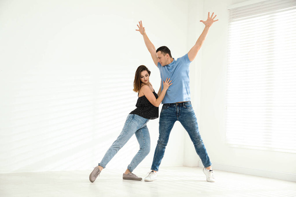 Beautiful young couple dancing in empty studio - Foto, imagen
