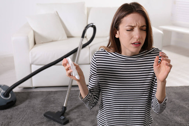 Young woman suffering from dust allergy while vacuuming house - Foto, Bild