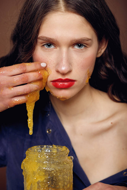 Girl with jar of honey. Healthy food concept, diet, dessert. Beautiful woman with honey on her face. Healthy perfect skin. Honey treatment. - Zdjęcie, obraz