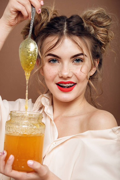 Girl with jar of honey. Healthy food concept, diet, dessert. beautiful girl smile holds a silver spoon with honey - Foto, imagen