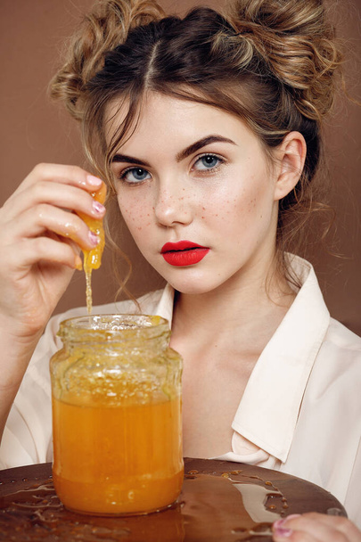 Girl with jar of honey. Healthy food concept, diet, dessert. beautiful girl smiles and touches honey with hands from a jar - Zdjęcie, obraz