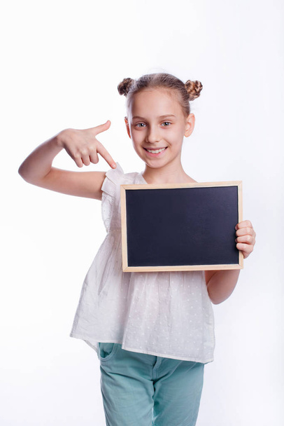 Kleines Mädchen mit leerem Brett auf weißem Hintergrund. Das Kind zeigt ein leeres Brett. Bildungskonzept - Foto, Bild