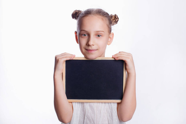 Kleines Mädchen mit leerem Brett auf weißem Hintergrund. Das Kind zeigt ein leeres Brett. Bildungskonzept - Foto, Bild