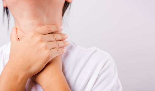 Asian beautiful woman Sore Throat or thyroid gland problem her useing Hand Touching Ill Neck on white background with copy space, Medical and Healthcare concept - Photo, image