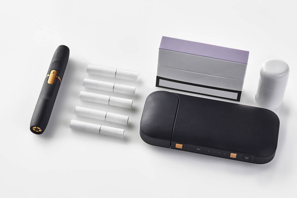 Neue Generation schwarzer Akku für elektronische Zigaretten, Reiniger, Packung mit lila Seite, fünf Heatsticks isoliert auf weiß. Tabakheizung. Nahaufnahme - Foto, Bild