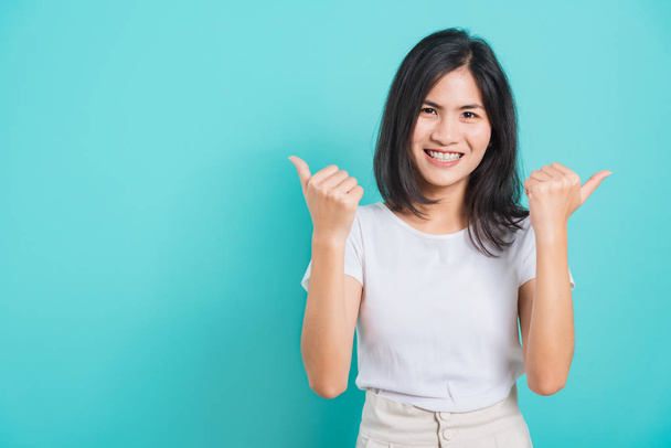 Portrait Asian beautiful happy young woman smile white teeth wear white t-shirt standing successful woman giving two thumbs up gesture, on a blue background with copy space - Valokuva, kuva