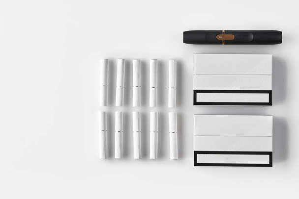 cigarette électronique noire de nouvelle génération, deux paquets et dix bâtons de chaleur isolés sur blanc. Espace publicitaire. Chauffage du tabac. Gros plan
 - Photo, image